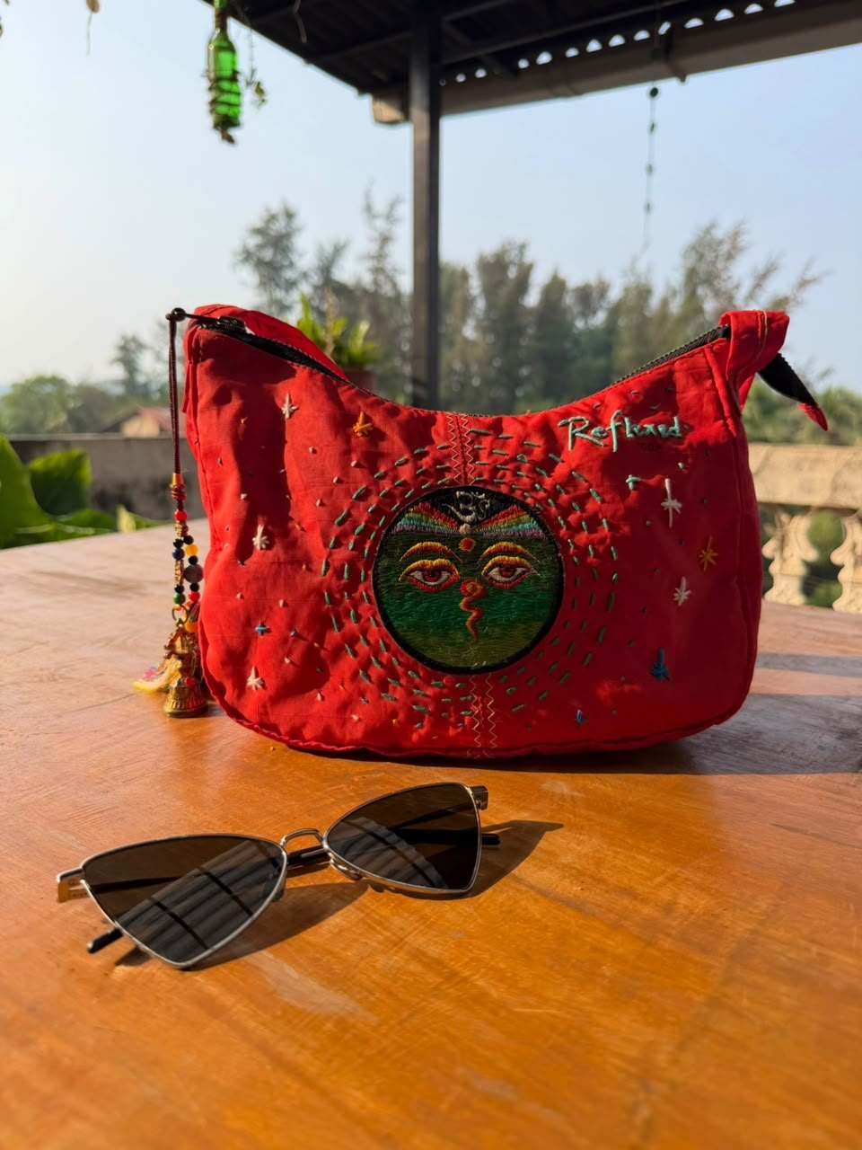 Red shoulder bag made from a retired kitesurf sail, hand-embroidered with a pair of eyes